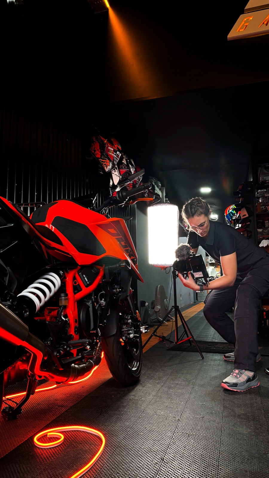 Rodaje de PlannerTeam en CR Garage: una KTM Duke naranja iluminada y una camarógrafa filmándola